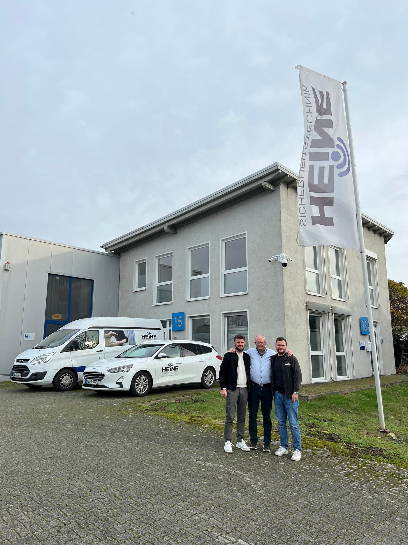 Ralf, Benjamin und Niklas Heine vor dem Firmengebäude von Heine Sicherheitstechnik in Borchen mit den Servicefahrzeugen